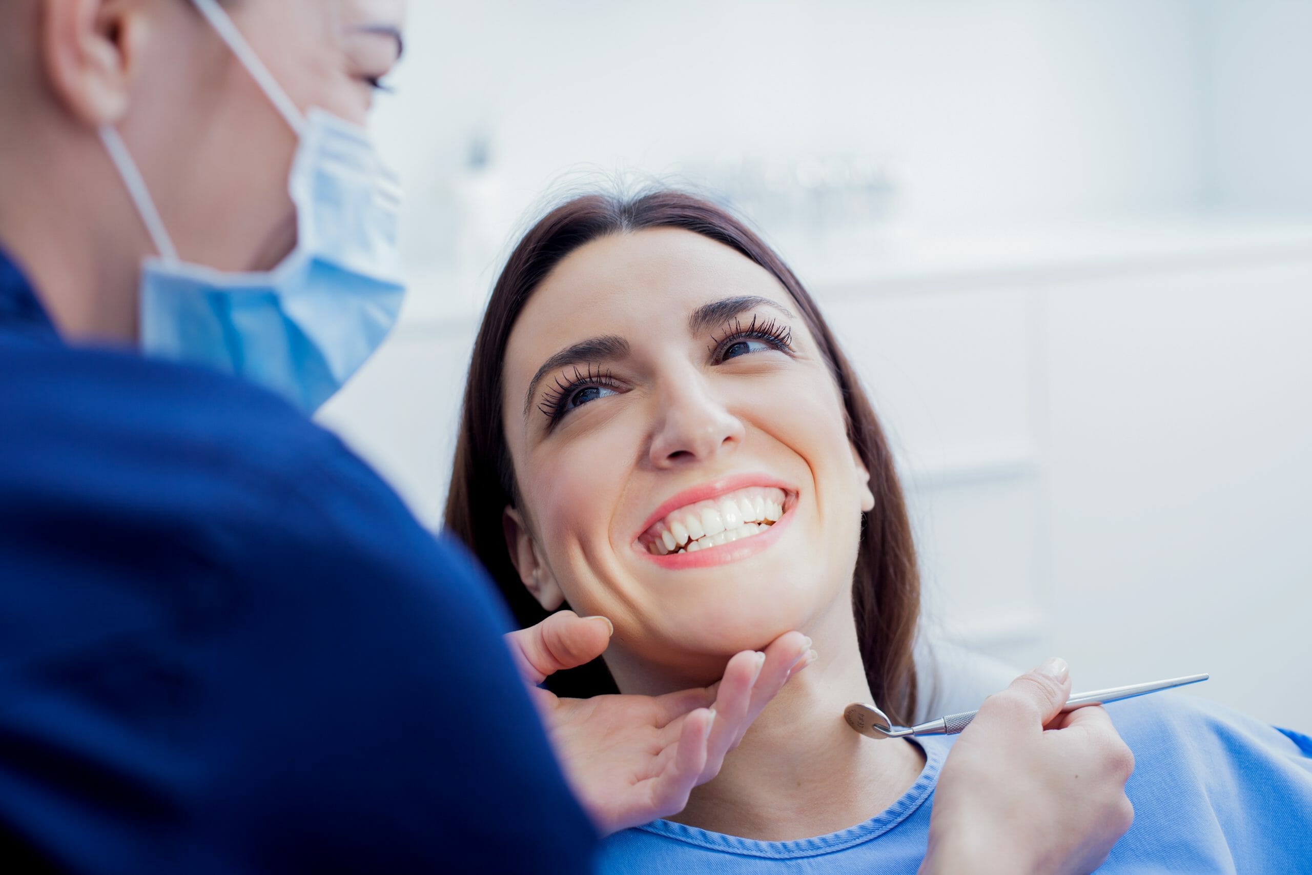 Dentist working on smiling patient with mirror in hand